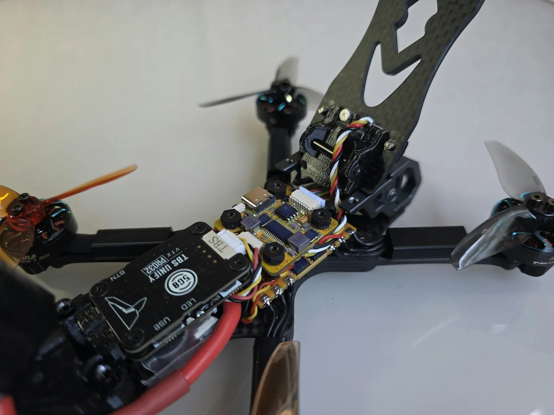 Open FPV drone showing circuit boards, motor wiring, battery, and propellers
